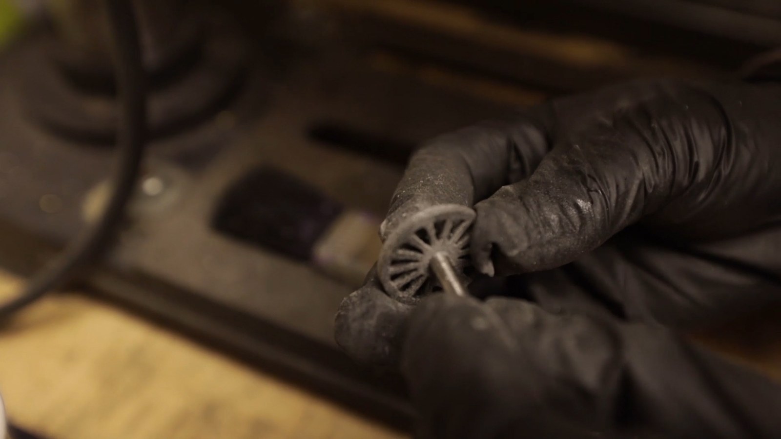 A gloved hand assembling the miniature locomotive with tweezers
