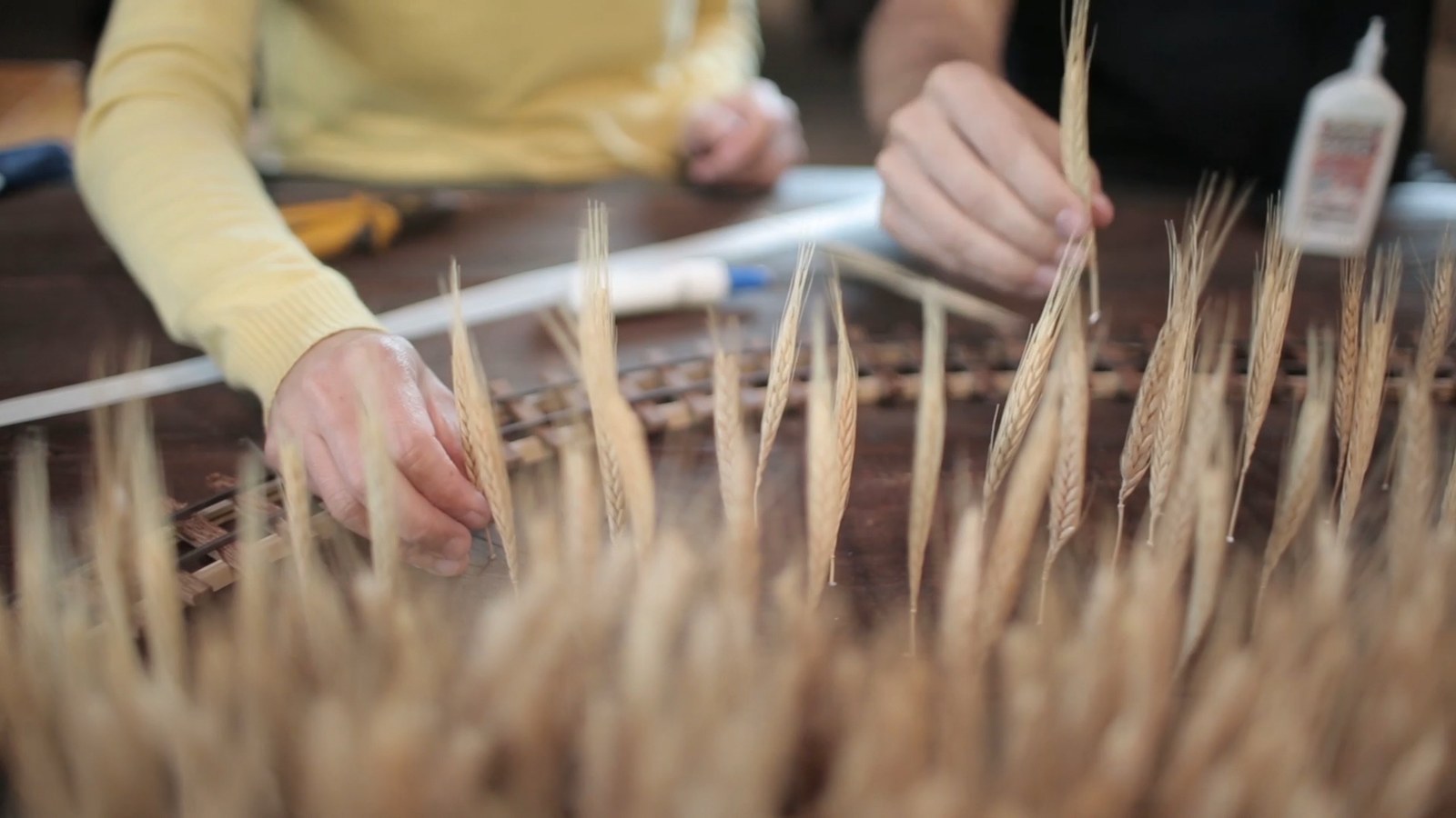 A hand gluing individual wheat stalks onto the miniature set