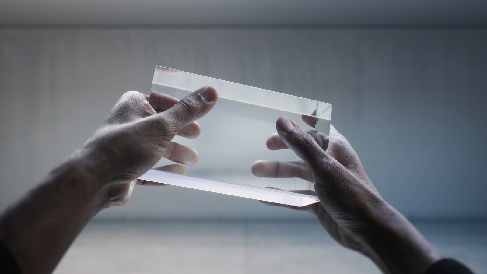 Two hands holding the glass block in a bare concrete room
