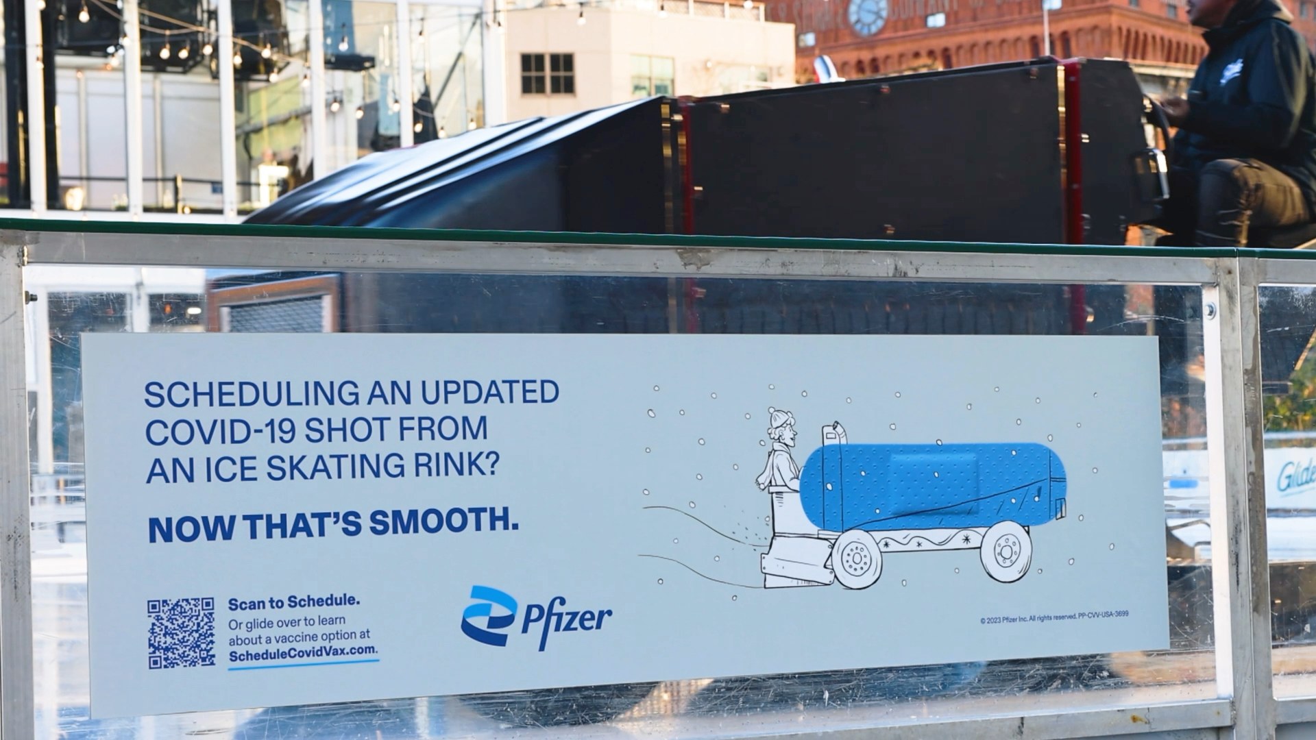A bus shelter poster about scheduling a COVID-19 shot from an ice skating rink