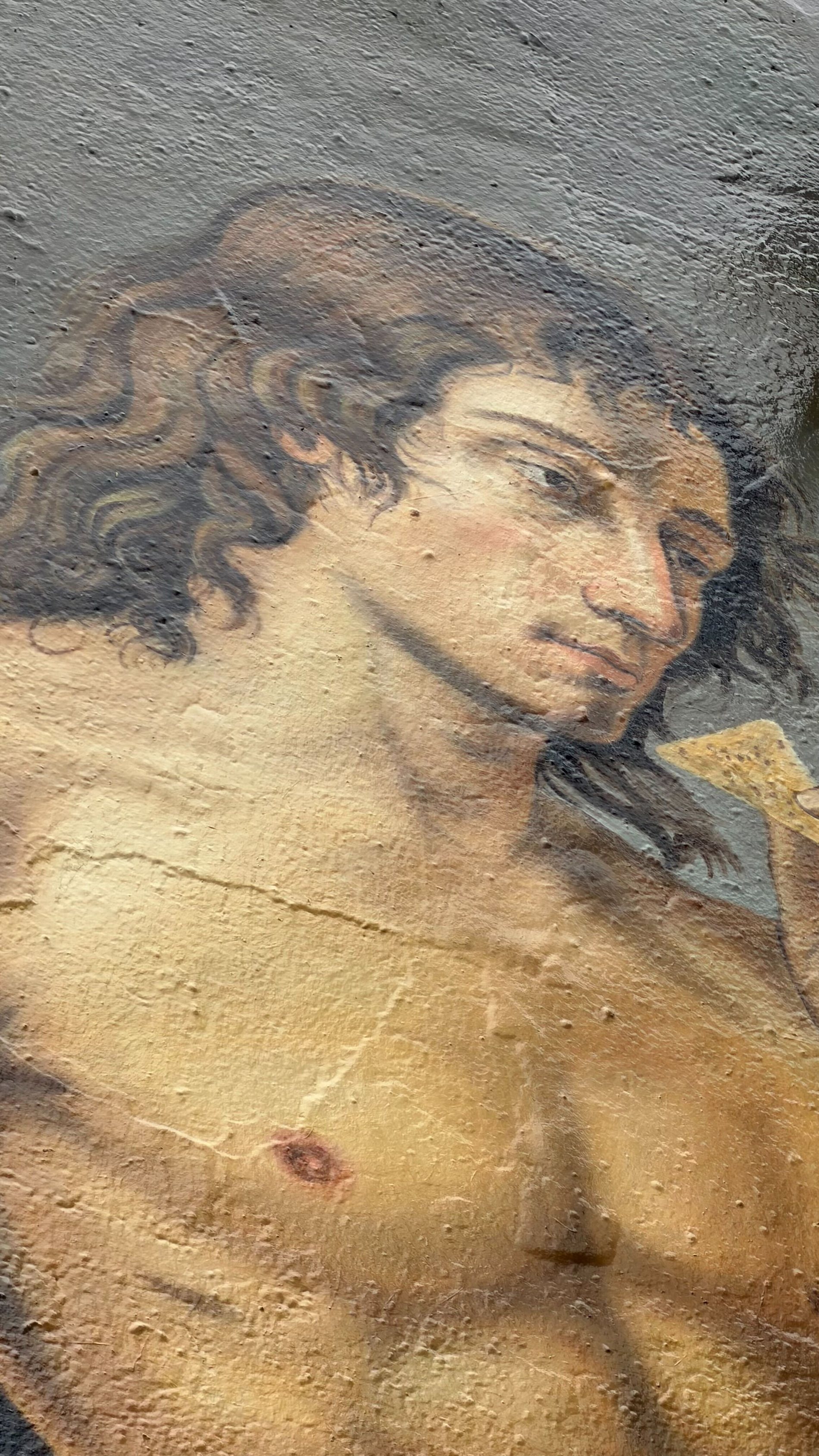 Detail of the mural, the painted face and shoulder against the wall texture