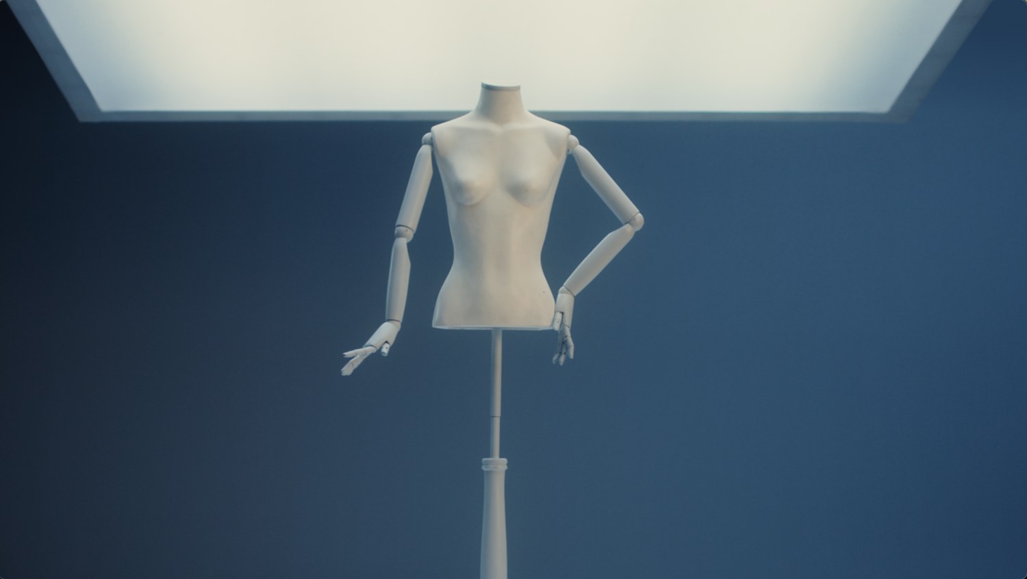 An empty dress form standing under the same light panel