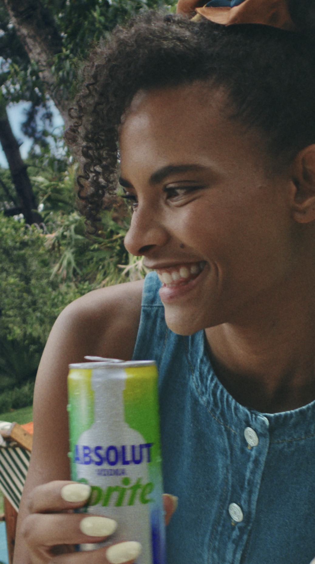 A woman laughing in a garden holding an Absolut Sprite can, vertical film by LOBO