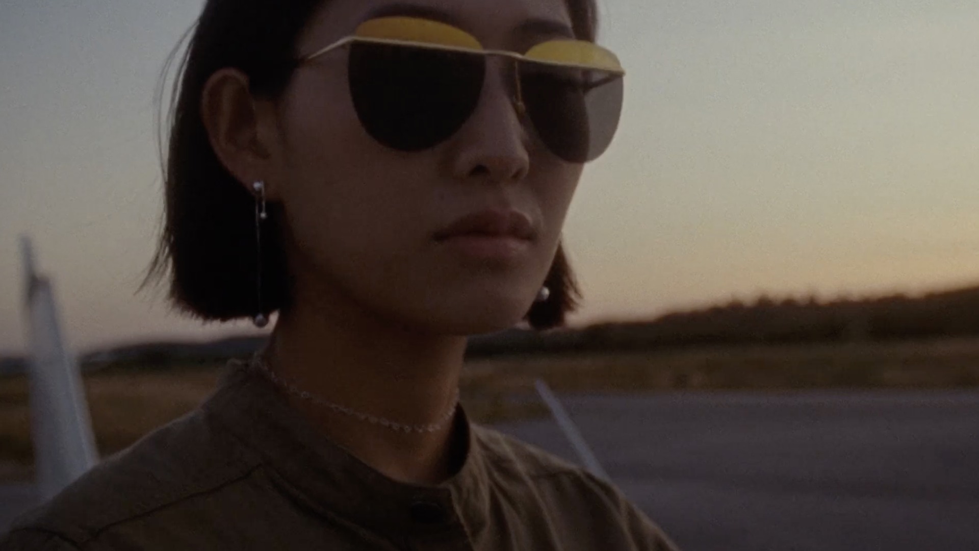 A woman in sunglasses at golden hour wearing Pandora jewellery